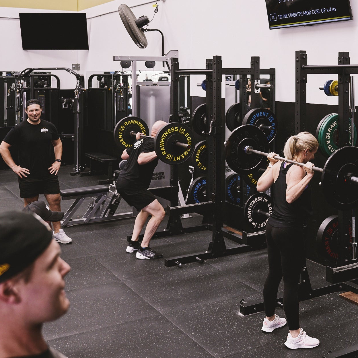 People working out with barbells in a gym setting